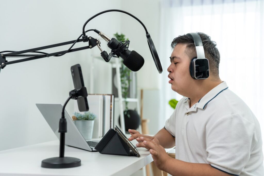 Young down syndrome DJ man wearing headphone and speak on microphone at studio.